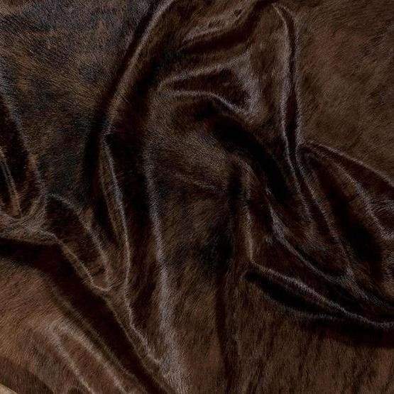 A Cowhide Rug in a Dark Brindle pattern, with brown and whites shapes
