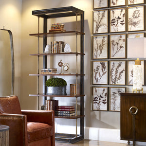 A very cozy room, with a leather arm chair a six shelf bookcase and a gold-plants wall art