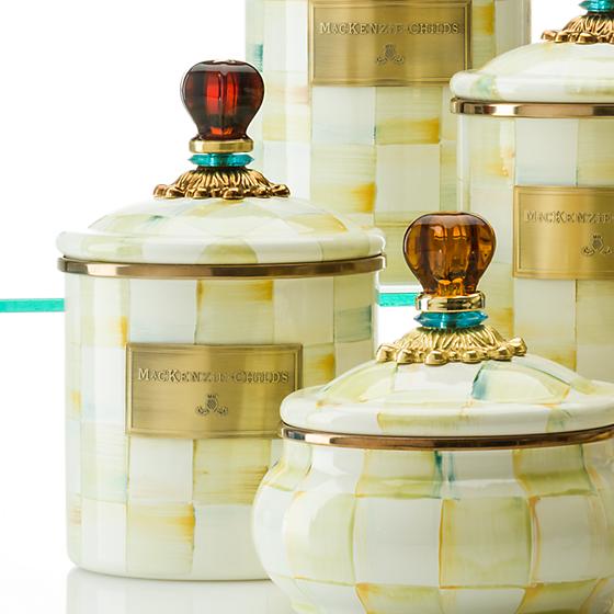 A set of cookie jars, with gold details and a golden Mackenzie Childs plate, perfect for kitchen organization and food storage