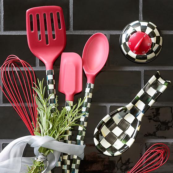 Set of red utensils and a bunch of fresh herbs on a black tile background.