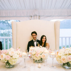 The bride and the groom setting on a double high-back white sofa