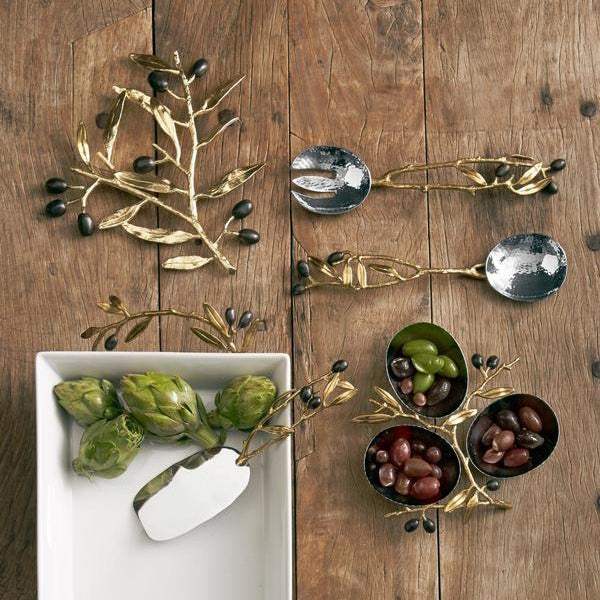 A set of serving pieces with olive branches design on top of a wood table