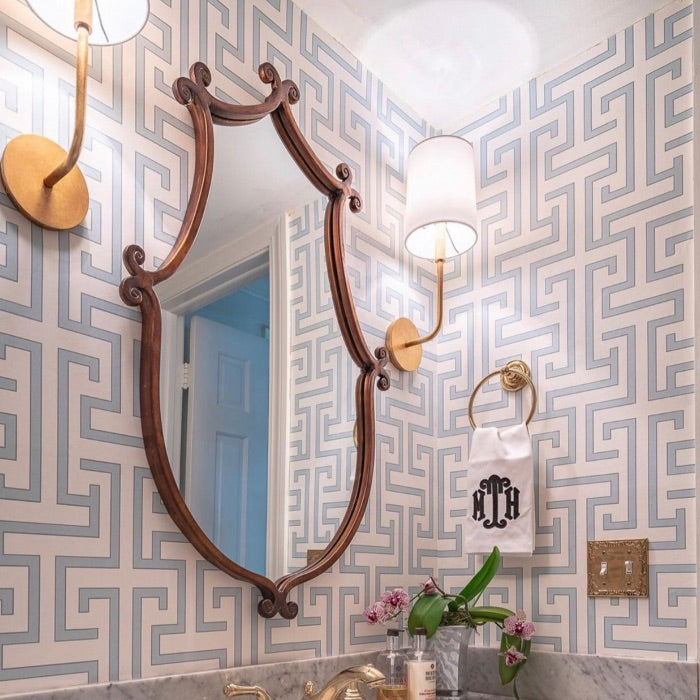 A classic vanity mirror with two vanity lights on the sides and a geometric pattern wallpaper gives a modern look to the scene.