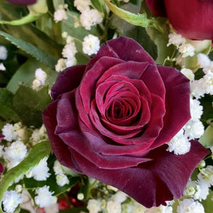 A dozen lush red roses and bb in a double vase with Red Hot Cinnamon Candies inside the vase and a red wire. The valentine floral arrangement is spinnig in the video. the candies have a heart shape. also some candies on the table