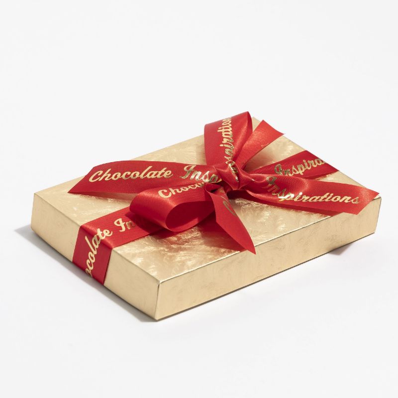 Box of chocolate in a golden color with a red ribbon