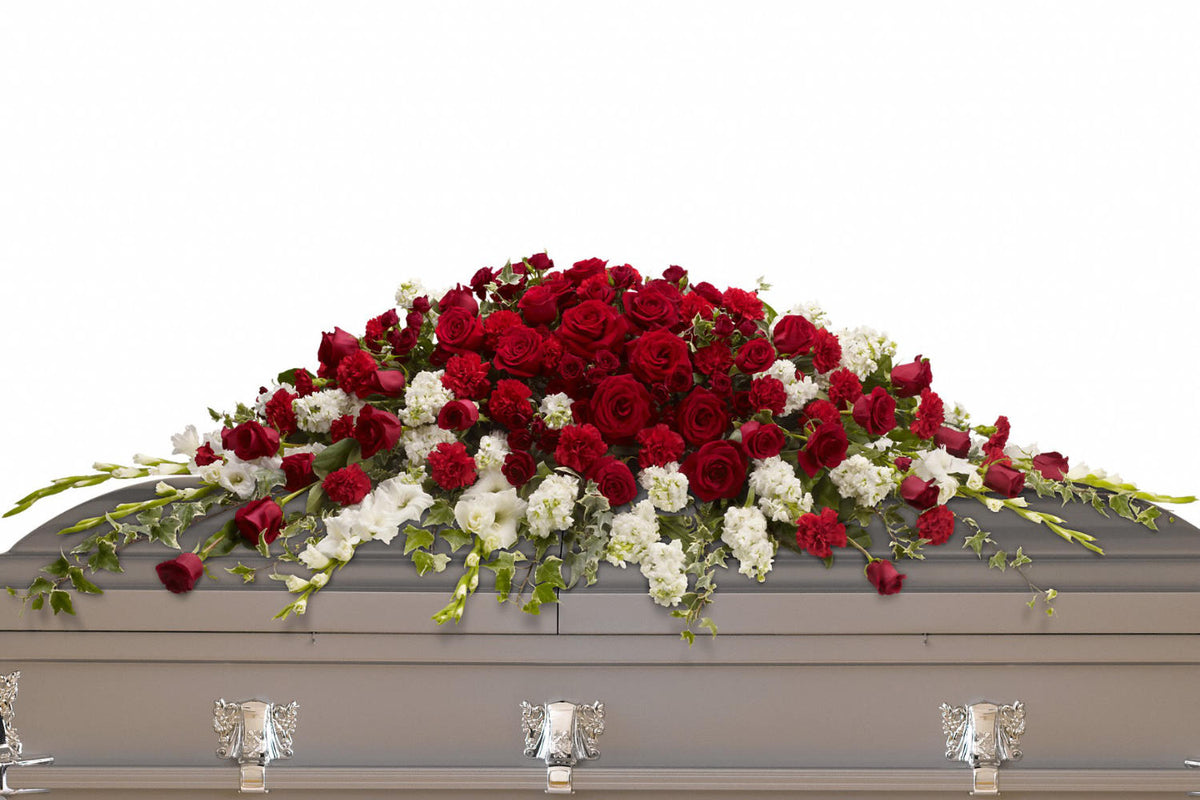 Beautiful funeral flowers. A casket spray with red roses and white flowers on top of a grey casket