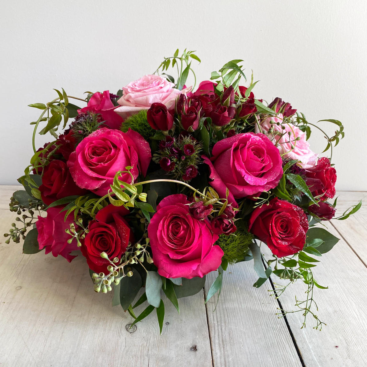 A Jaw-dropping floral design that showcases the pure beauty of a rose. A stunning arrangement of paved mixed roses and greens. Featuring red hearts roses. Pink Floyd Roses and romantic O&#39;Hara garden roses. Topped with a touch of glitter.